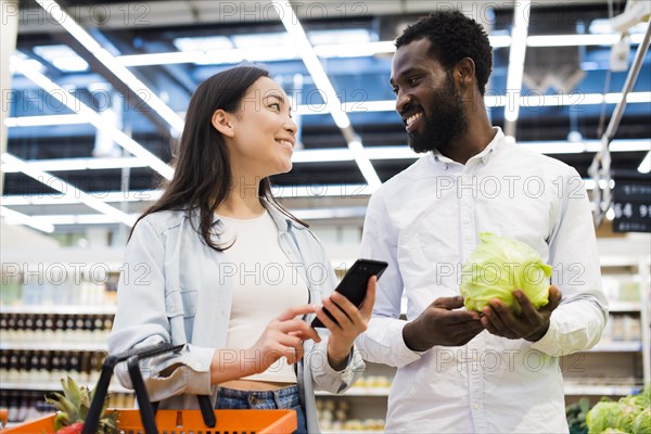 Happy multiracial couple choosing goods looking each other supermarket