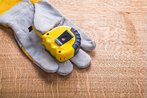 Yellow measuring tape on the front of the protective glove and the wooden board