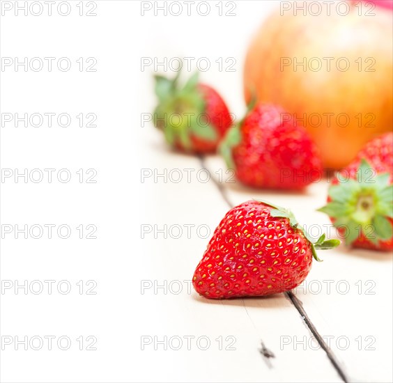 Fresh fruits apples pears and strawberry on a white wood table