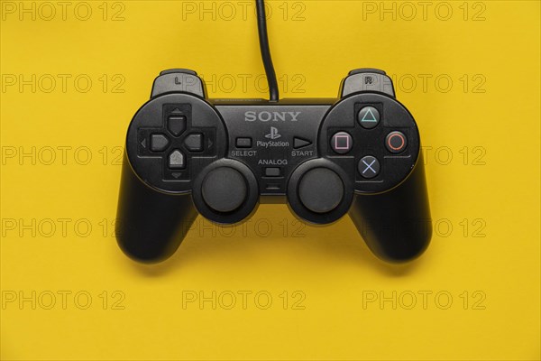 Controller of the PS2 Playstation game console from Sony in front of a monochrome yellow background