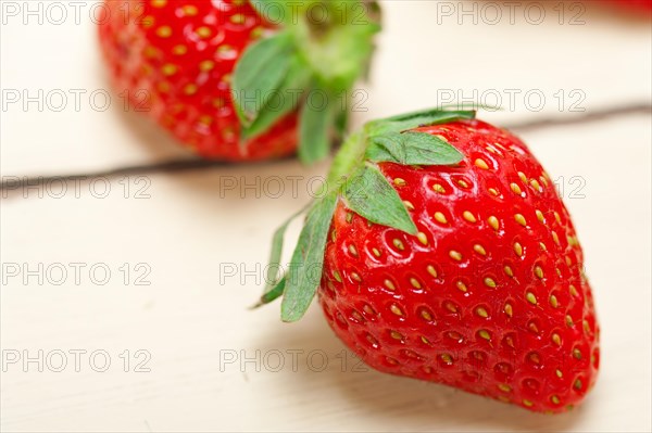 Fresh organic strawberry over white rustic wood table