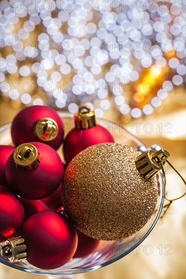 Golden and red Christmas baubles in a wine glass up close