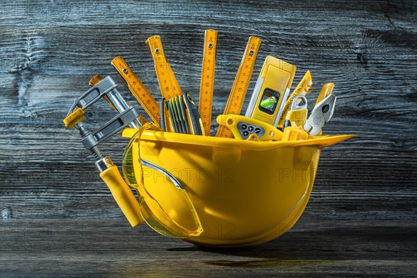 Construction tools in helmet on gray wood