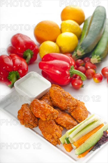 Classic buffalo chicken wings served with fresh pinzimonio and vegetables on background