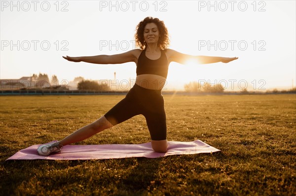 Woman goes in for sports gymnastics yoga at dawn on the grass