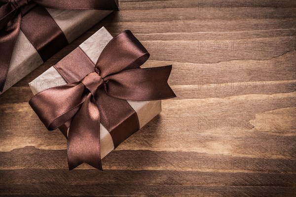 Wrapped present containers with brown ribbons on vintage wooden board