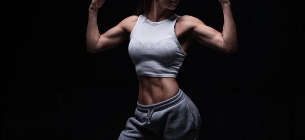 Athletic fitness woman posing in the studio on a dark background. Photo of an attractive woman in fashionable sportswear. Sports and healthy lifestyle. Mixed media