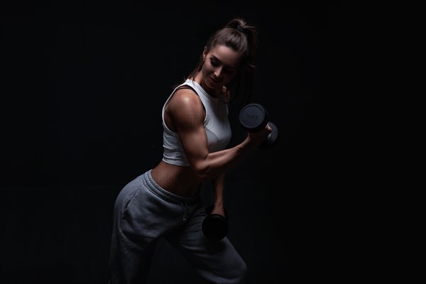 Athletic fitness woman posing in the studio on a dark background. Photo of an attractive woman in fashionable sportswear. Sports and healthy lifestyle. Mixed media