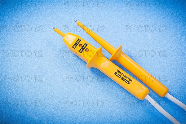 Yellow electrical tester isolated on blue surface electricity concept