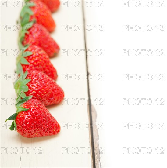 Fresh organic strawberry over white rustic wood table