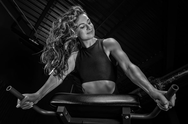 Charming brunette doing hyperextension in the gym. Press pumping. Fitness and bodybuilding concept.