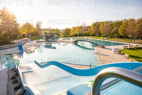 Sunny spring day in a public swimming pool with slides and water basin