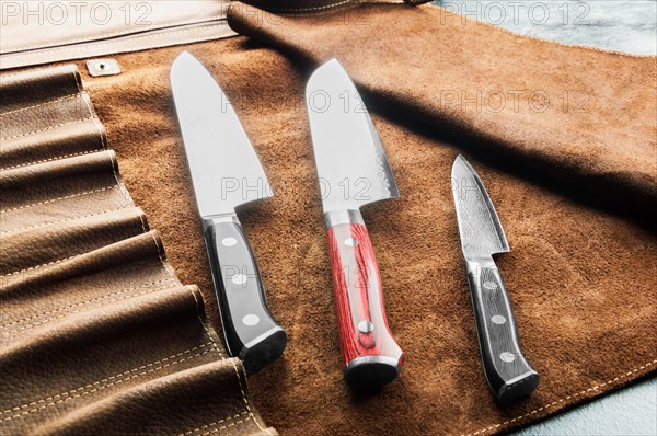 Japanese knives of different sizes from Damascus steel are in a leather case. Business concept of career growth