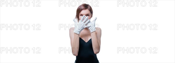 Confused girl in white gloves posing in the studio on a white background. No name portrait.