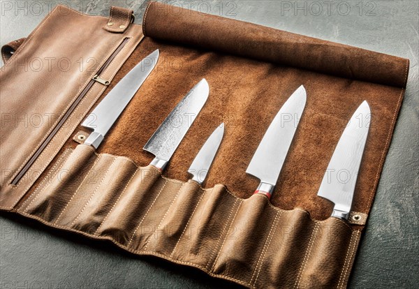 Japanese knives of different sizes from Damascus steel are in a leather case. Business concept of career growth