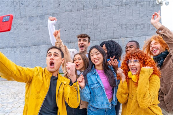 Excited group of multi-ethnic friends celebrating while taking a selfie outdoors