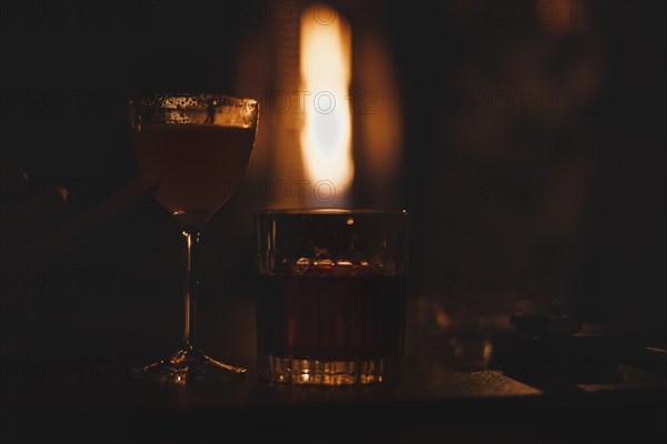 Image of a glass with a cocktail in a night bar against the background of a fiery heater. Restaurant concept