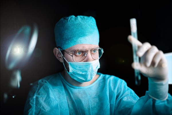 Scientist doctor in a dark laboratory with a test tube of a medicinal product