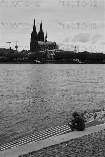 View over the Rhine with cathedral and lone person in front of it, black and white, Cologne, Germany, Europe