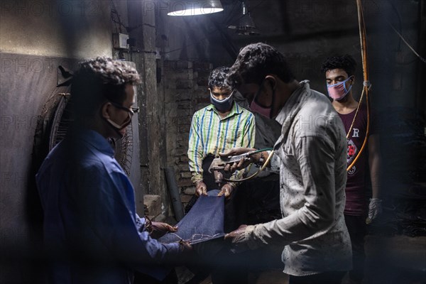 Workers colouring a pair of jeans in a textile factory, Dhaka, Bangladesh, Asia