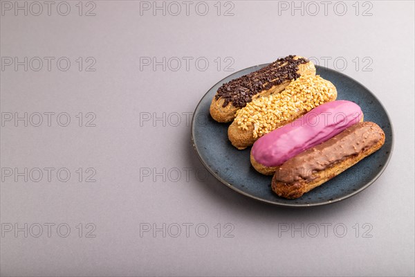 Set of eclair, traditional french dessert on blue ceramic plate on gray pastel background. side view, copy space, still life. Breakfast, morning, concept