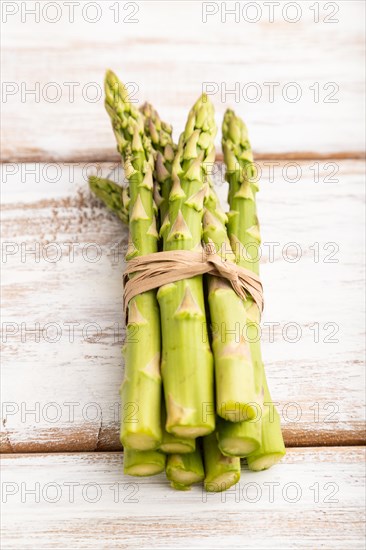Bunch of fresh green asparagus on white wooden background. Side view, close up. harvest, healthy, vegan food, concept, minimalism