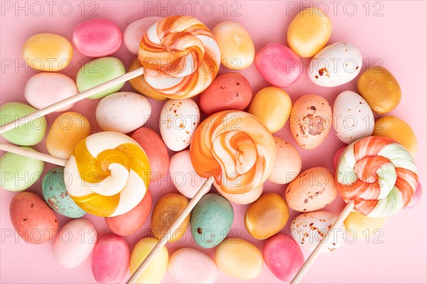 Various caramel candies on pink pastel background. close up, top view, flat lay