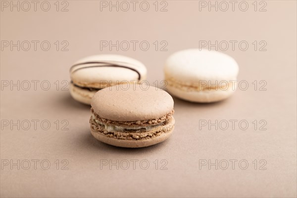 Brown and white macaroons on beige pastel background. side view, close up, still life. Breakfast, morning, concept