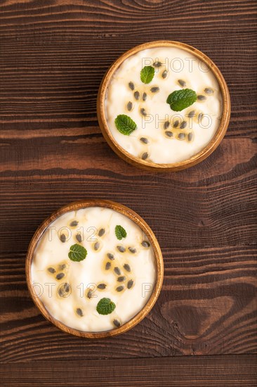 Yoghurt with granadilla and mint in wooden bowl on brown wooden background. top view, flat lay, close up