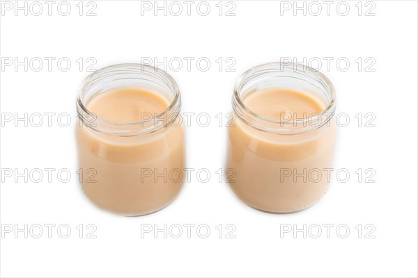 Baby puree with fruits mix, apple, banana infant formula in glass jar isolated on white background. Side view, close up, artificial feeding concept