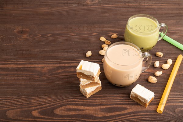 Bubble tea with pistachio and caramel in glass on brown wooden background. Healthy drink concept. Side view, copy space