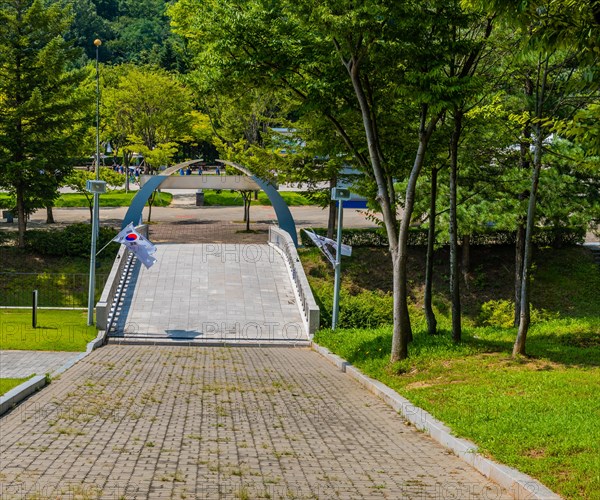 Brick walkway down hill to concrete bridge over ravine at Independence Hall park in Cheonan, South Korea, Asia