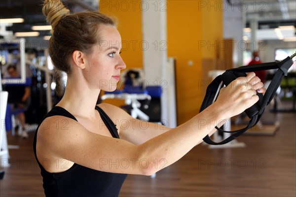 Young woman doing TRX training in the gym, (Neuhofen, Rhineland-Palatinate)