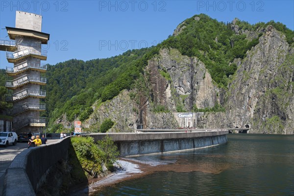 Building on a reservoir with forest and rock formations in the background