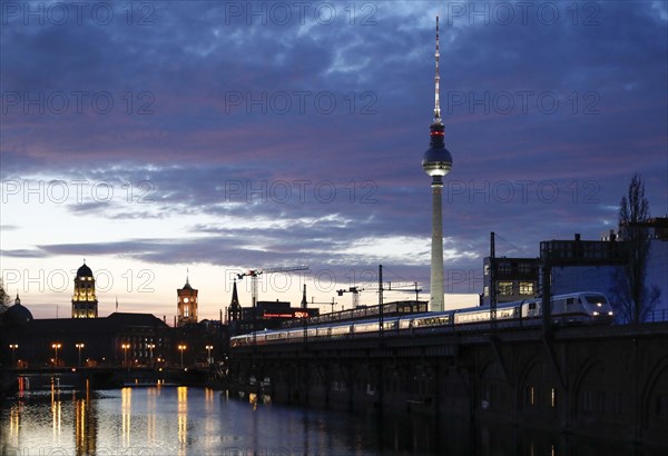 City view Berlin in the evening. View across the Spree to the television tower and the red town hall, a Deutsche Bahn ICE at the S-Bahn station at Janowitzbruecke, 29/03/2021