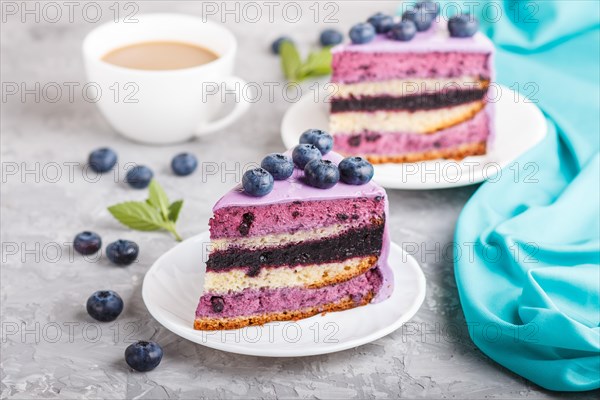 Homemade cake with souffle cream and blueberry jam with cup of coffee and fresh blueberries on a gray concrete background. side view, selective focus, close up