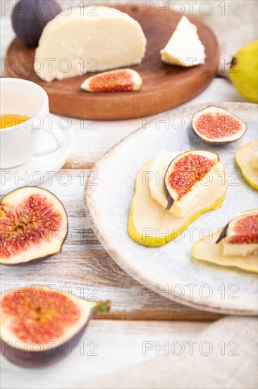 Summer appetizer with pear, cottage cheese, figs and honey on a white wooden background and linen textile. Side view, close up, selective focus