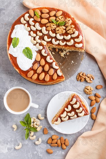 Homemade cake with caramel cream and nuts with cup of coffee on a gray concrete background. top view. flat lay, copy space