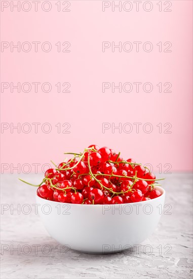Fresh red currant in white bowl on gray and pink background. side view, copy space, selective focus
