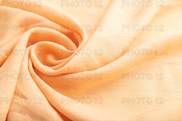 Fragment of orange linen tissue. Side view, natural textile background and texture. wave concept, abstract, spiral form