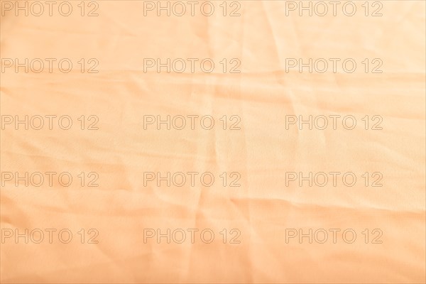 Fragment of smooth orange linen tissue. Side view, natural textile background and texture