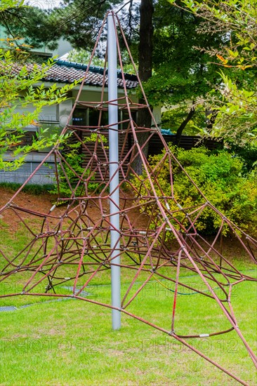 Rope pyramid playground equipment amidst a verdant outdoor setting, in South Korea