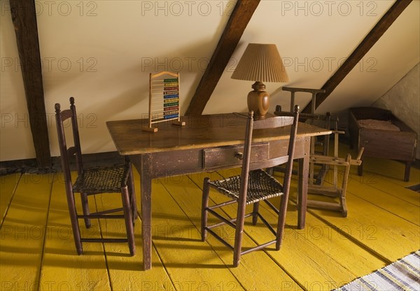 Old wooden children's play table and weaved rawhide seat chairs in bedroom on upstairs floor inside old 1785 home, Quebec, Canada, North America