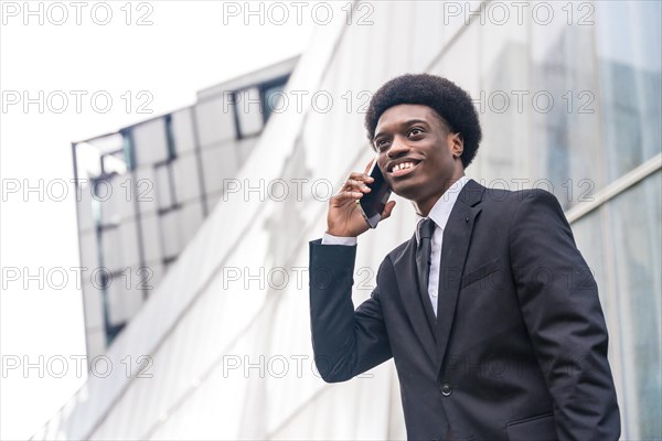 Low angle view close-up portrait with copy space of a Young african businessman using phone in the city