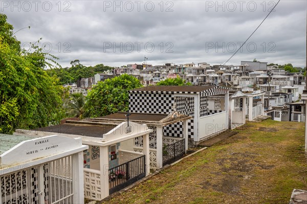 Famous cemetery, many mausoleums or large tombs decorated with tiles, often in black and white. Densely built buildings under a dramatic cloud cover Cimetiere de Morne-a-l'eau, Grand Terre, Guadeloupe, Caribbean, North America