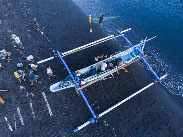 Fishermen unload their catch from their outrigger boat in the morning. Amed, Karangasem, Bali, Indonesia, Asia