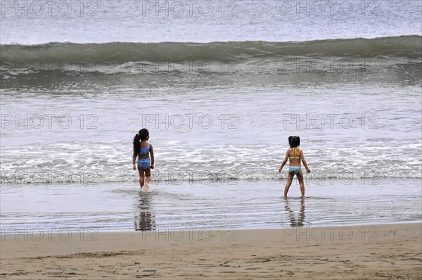 San Juan del Sur, Nicaragua, Two children playing on the beach near the water under a cloudy sky, Central America, Central America