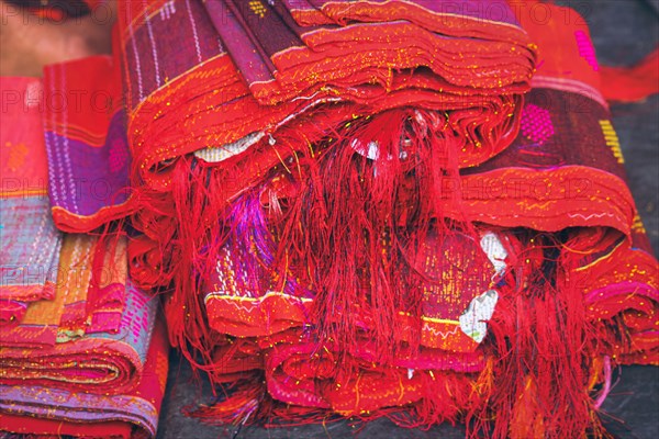 Close up to a stack of vibrant red Ulos fabric showcasing indigenous ethnic design showing the authentic culture and heritage of the Batak people from North Sumatra Indonesia