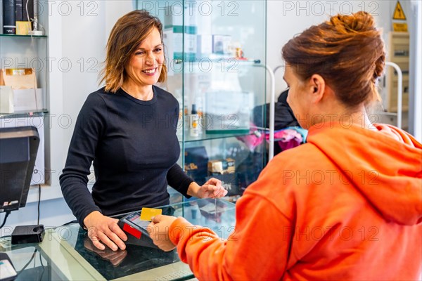 Rear view of a satisfied client paying using contact less credit card in a hair salon