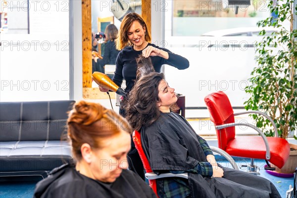 Hairdresser drying the hair of a relaxed woman in the salon